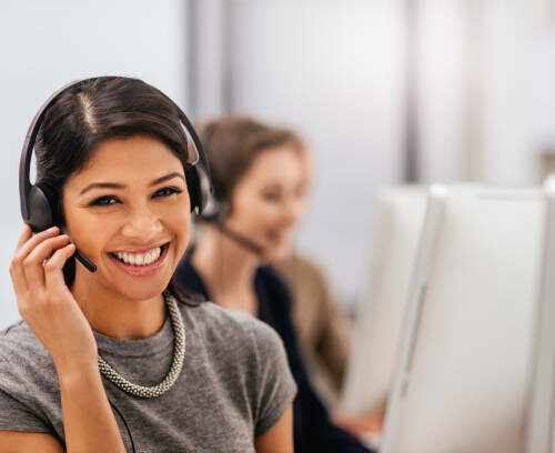 Portrait of a call centre agent working in an office with her colleagues in the background